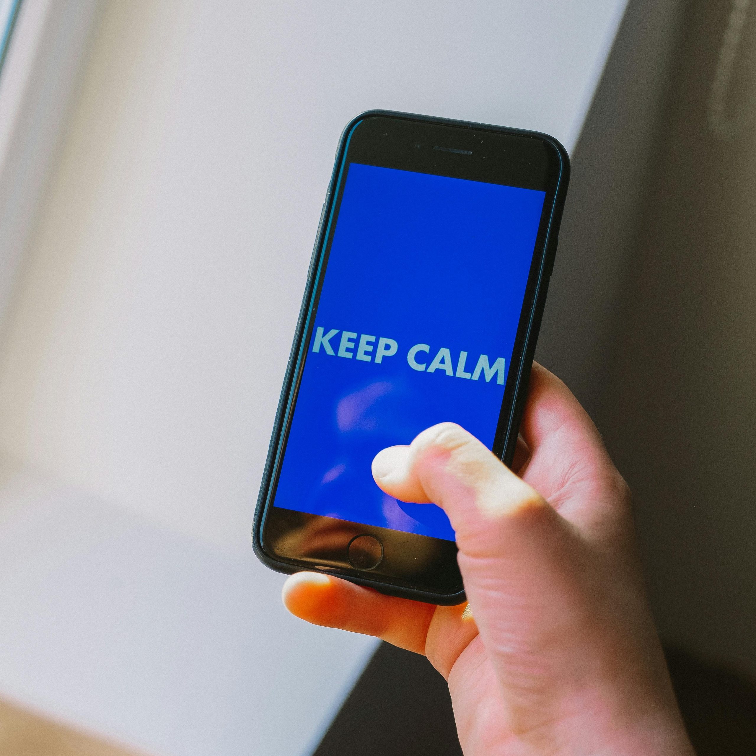 pexels-photo-4108213-4108213 Close-up of a hand holding a smartphone displaying 'Keep Calm'.