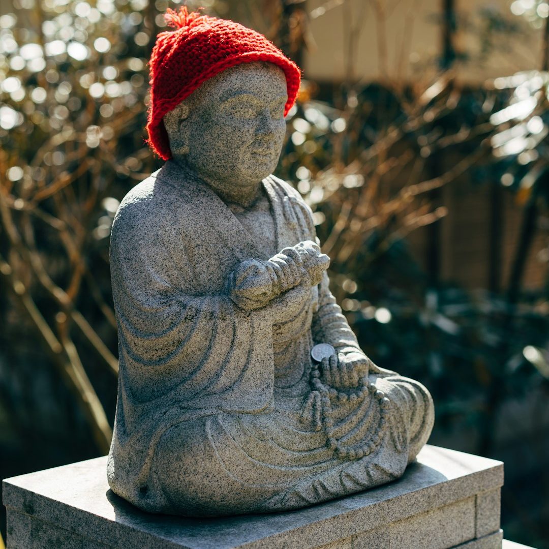 statue with a red hat and a coin in the hand in a temple on a mountain near Tokyo, Japan